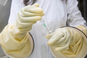 An expert wearing yellow gloves and holding an injection